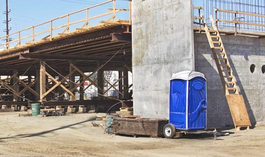 blue portable restrooms arranged in a neat line on a work site